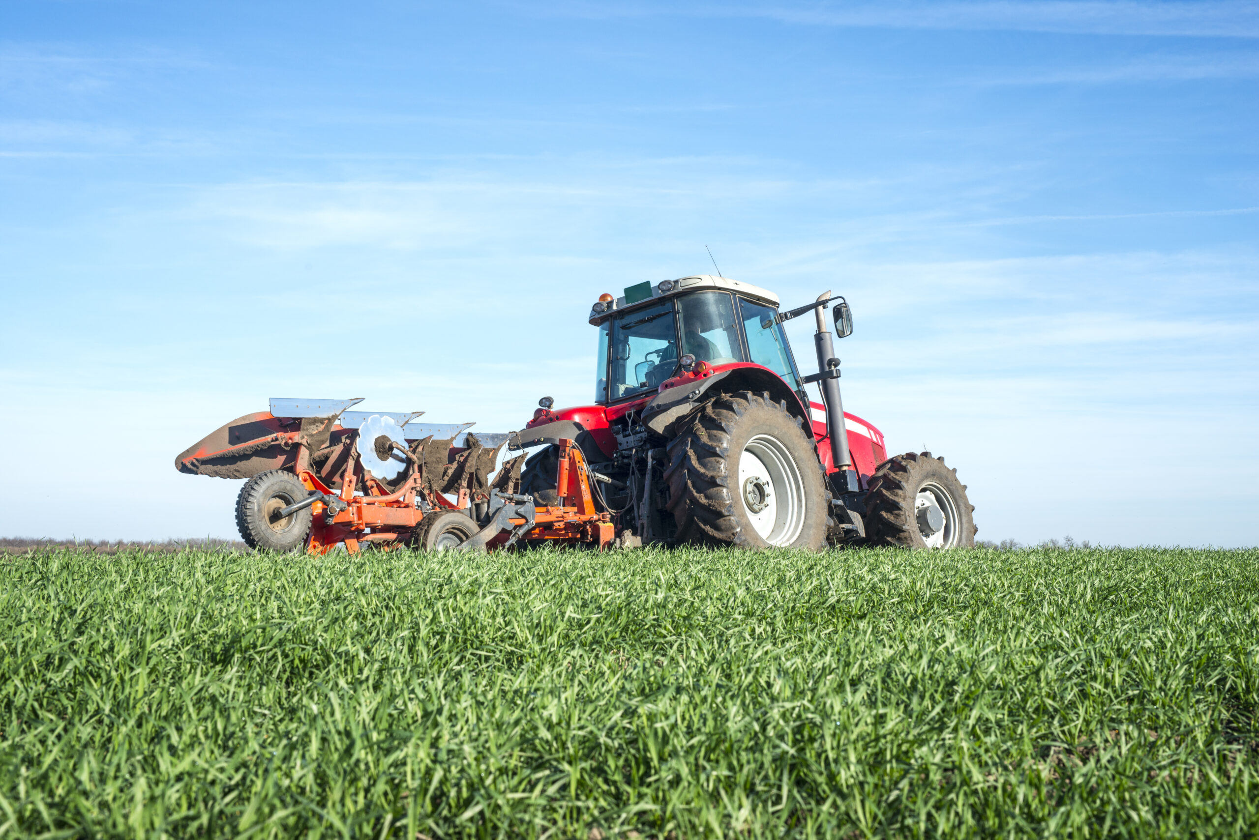 Tractor agricultural machine cultivating field.