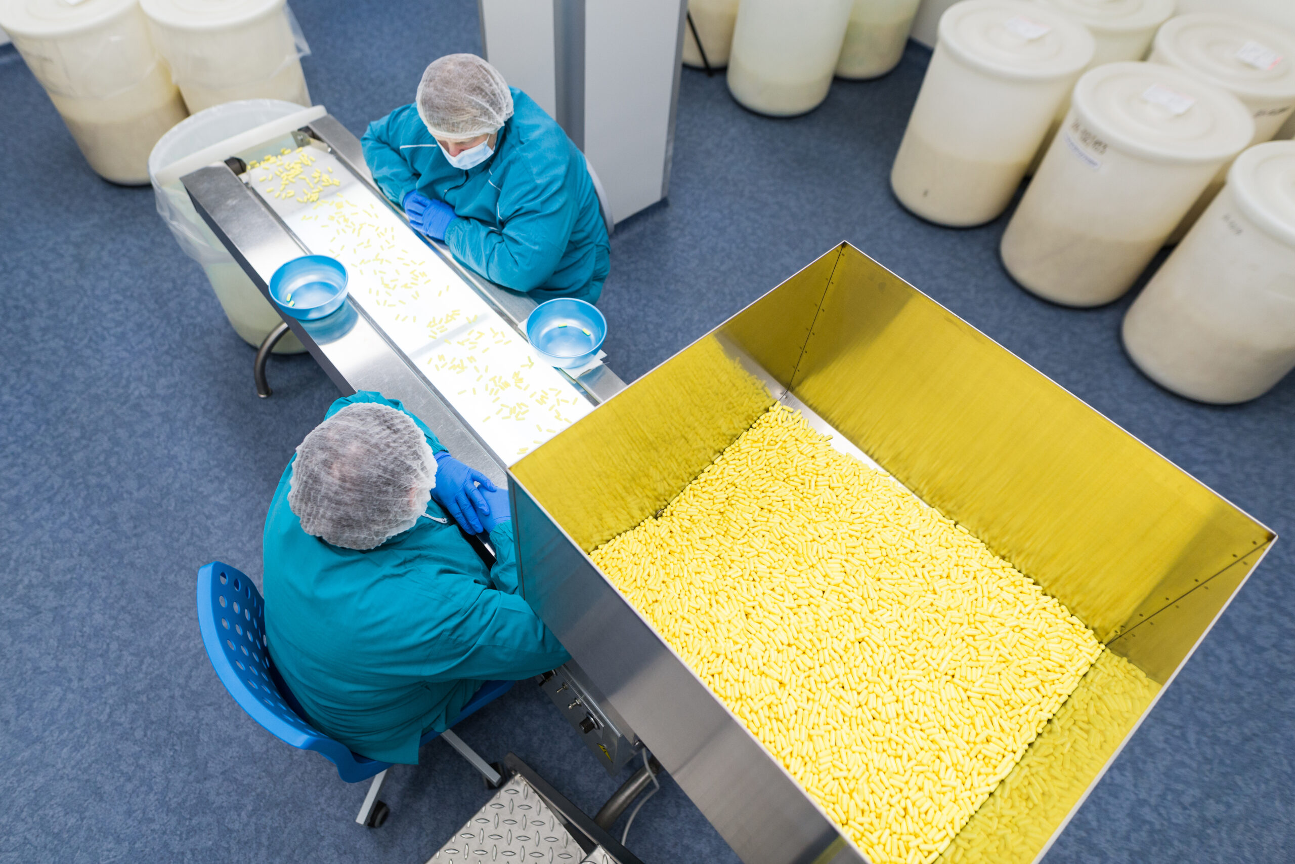 Two women in medical suits working on conveyor