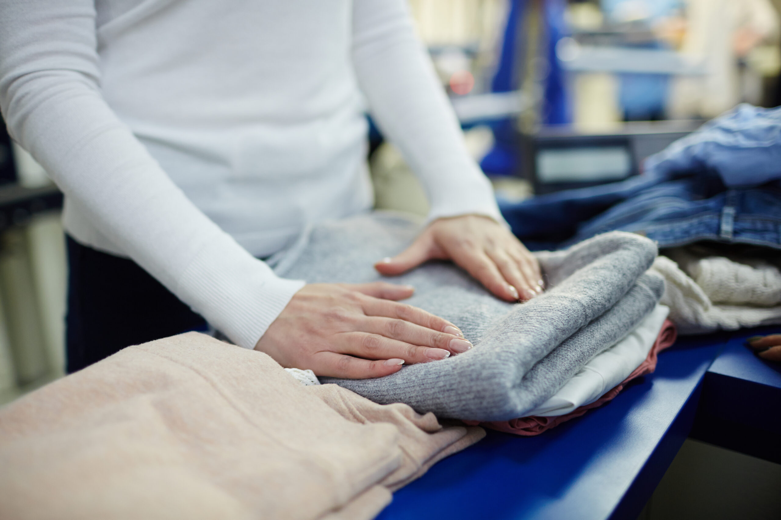 Woman folding clean clothes in dry-cleaning workshop